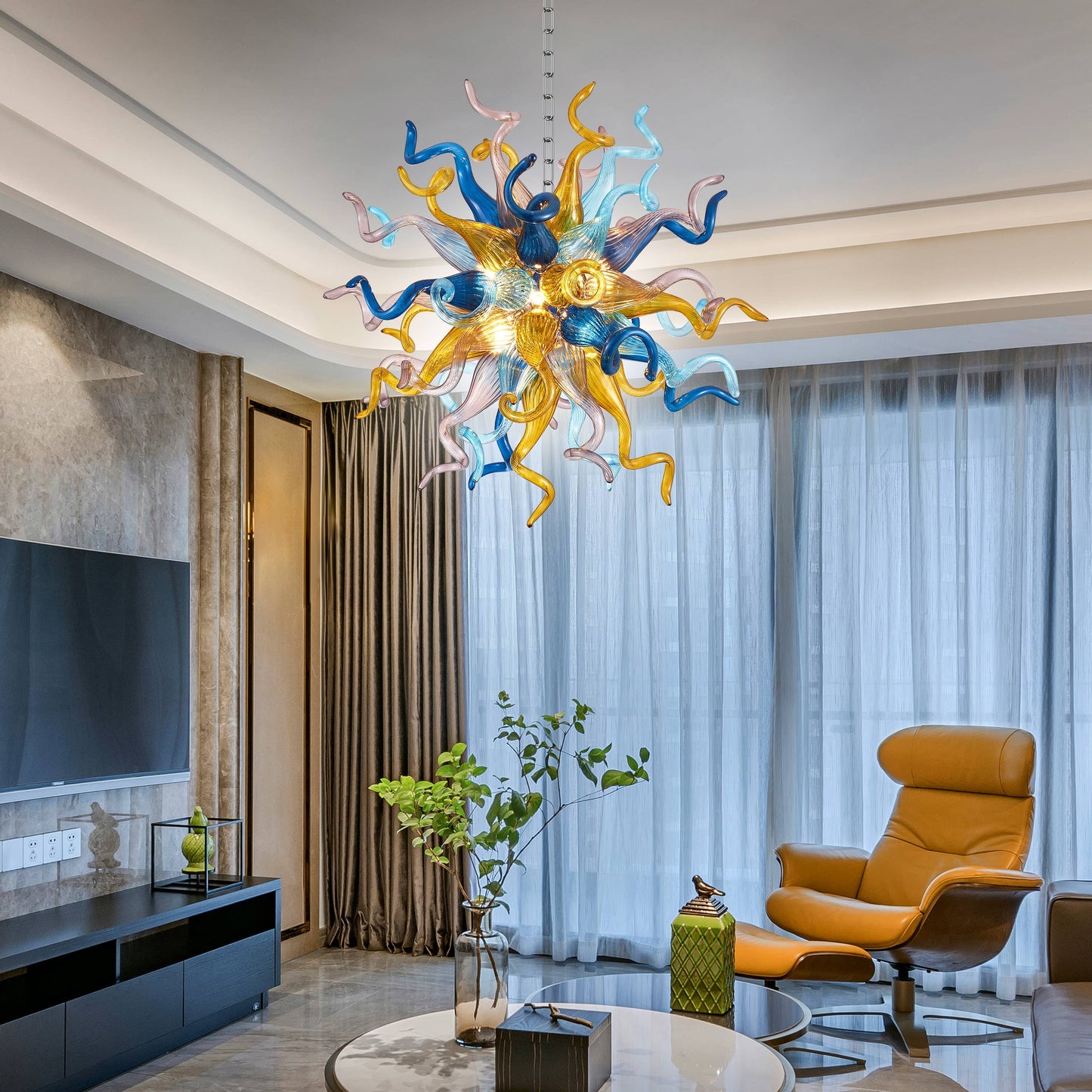 Chihuly style art chandelier hanging in a modern living room with a yellow armchair and large windows.