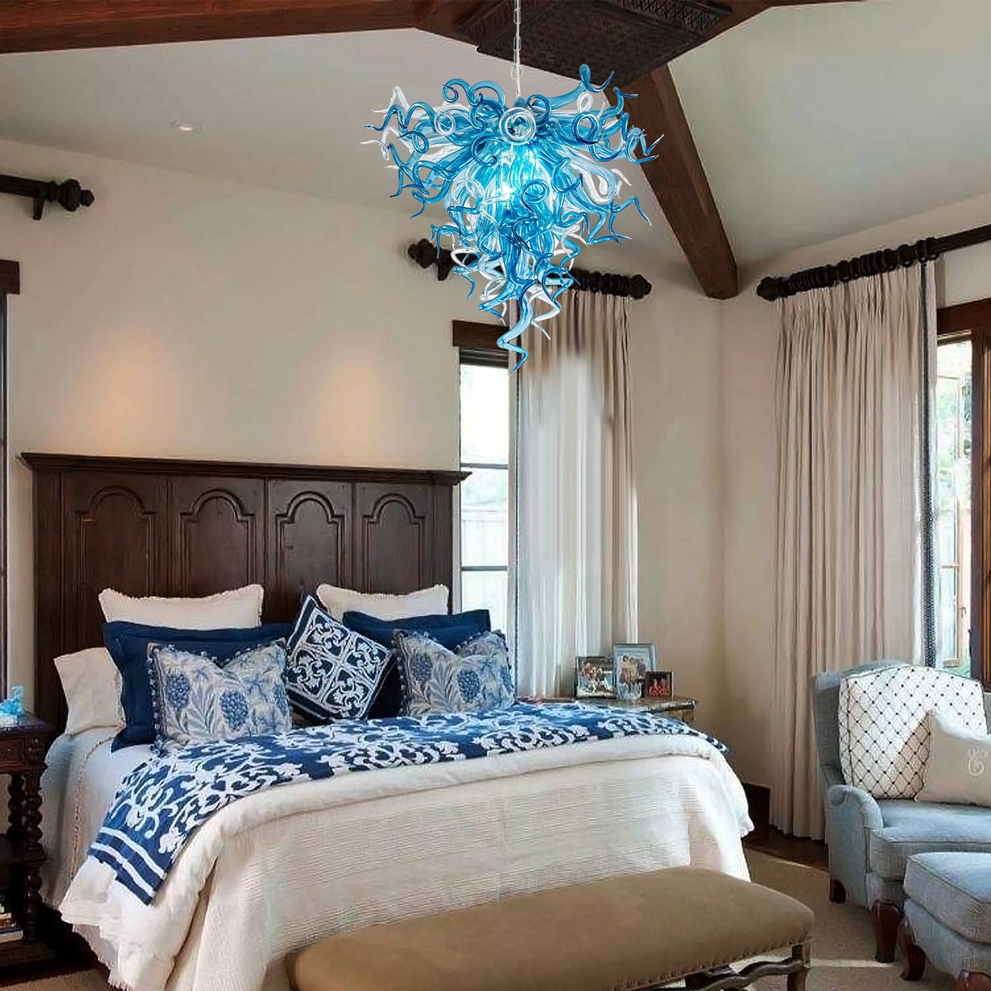 Luxurious bedroom with a large bed, blue and white bedding, and a decorative blue chandelier.
