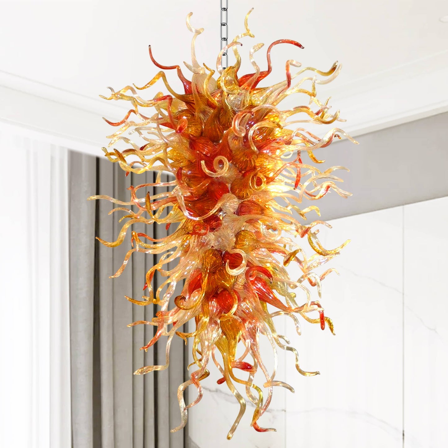 Fiery amber cascade hand blown glass chandelier as a vibrant focal point in light-colored background.