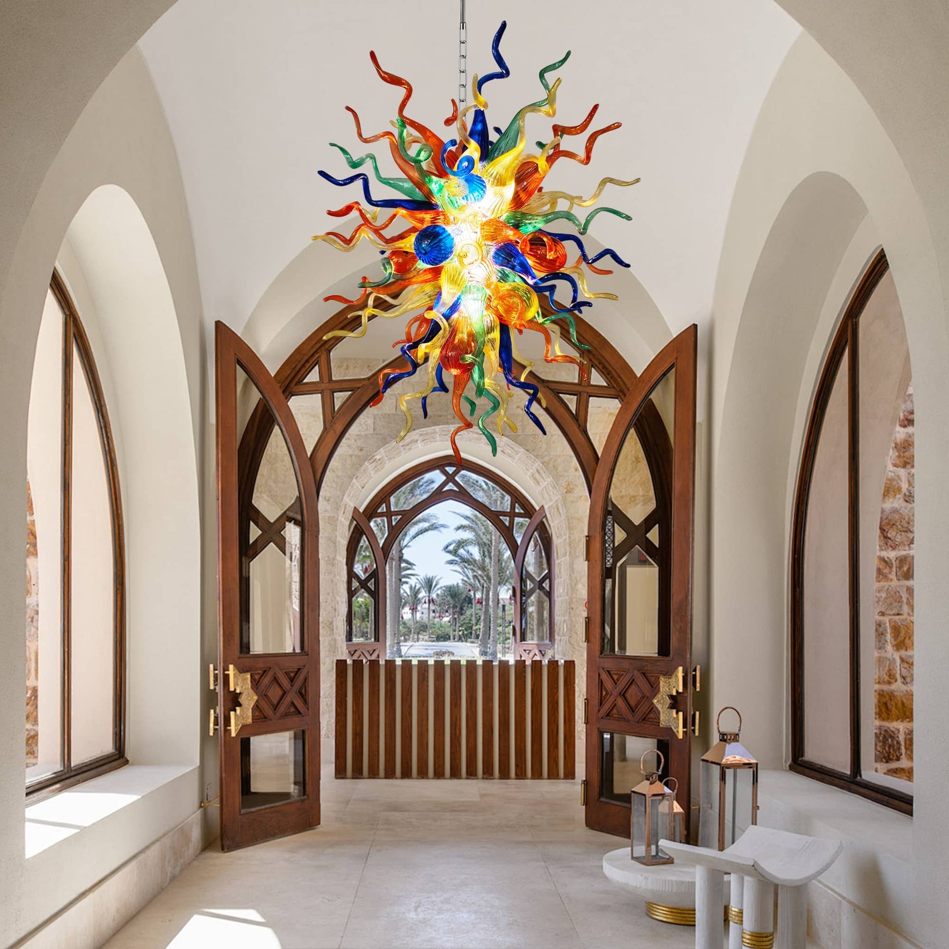 Vibrant multi-color hand blown glass chandelier as a striking focal point in a stylish home hallway with wooden doors and rustic furniture.