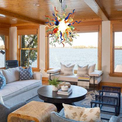 Vibrant hand blown glass chandelier hanging in a modern open-plan living space with outdoor views.