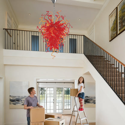 Red sculptural hand blown art glass chandelier in a bright, white two-story entryway.