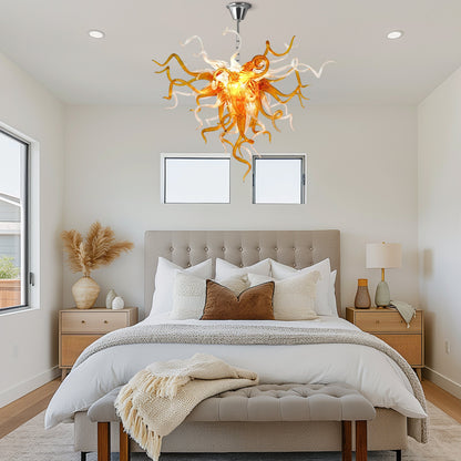 A Chihuly-style amber hand blown glass chandelier in a rustic bedroom.