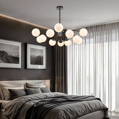 Warm-lit black 12-light frosted glass pendant bubble globe chandelier above dark-toned bedroom.
