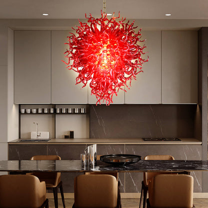 Artistic red hand blown glass chandelier illuminating a kitchen dining area.