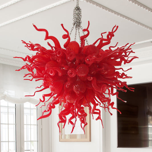  High-impact, colorful red hand blown glass chandelier installed in a bright, modern room.