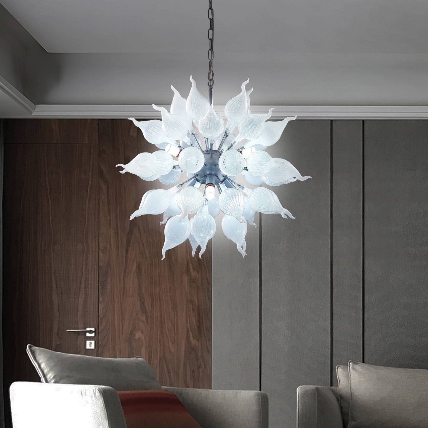 Modern sputnik blown glass chandelier hanging in a living room with gray walls and a sofa.