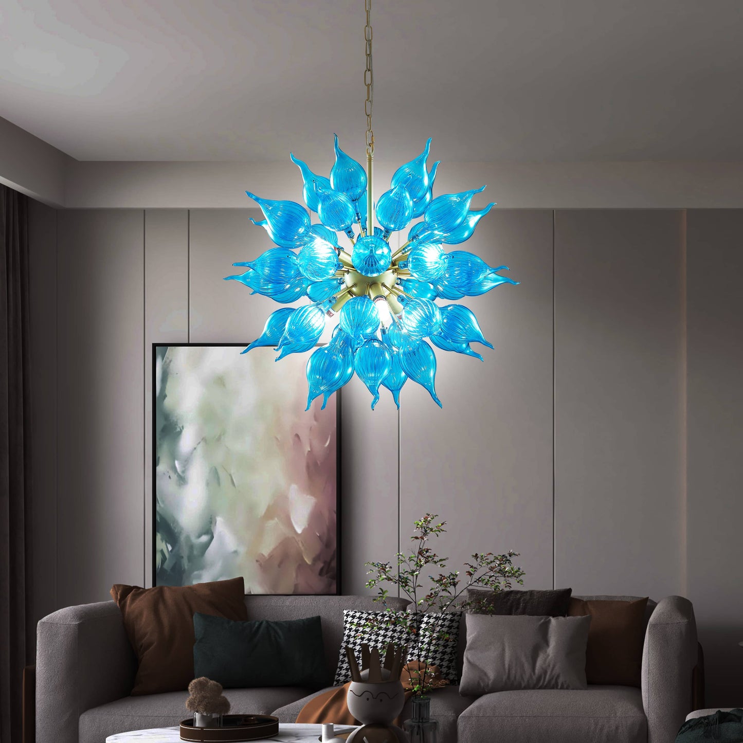 Blue floral blown glass chandelier in a living room setting with a sofa and artwork with cold light.