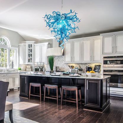 Modern kitchen with a blue chandelier, black island, and white cabinets.