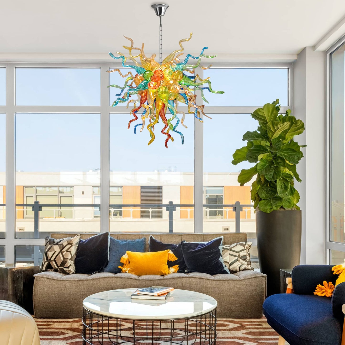 Modern living room with a multi colors Chihuly chandelier, gray sofa, and large windows.