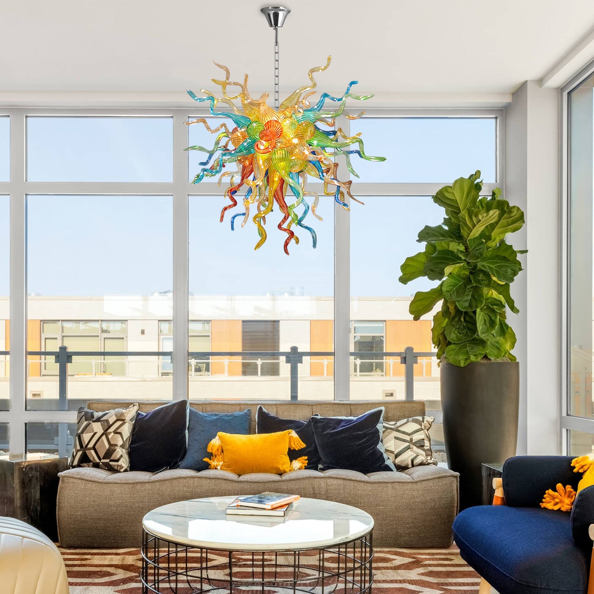 Modern living room with a multi colors Chihuly chandelier, gray sofa, and large windows.