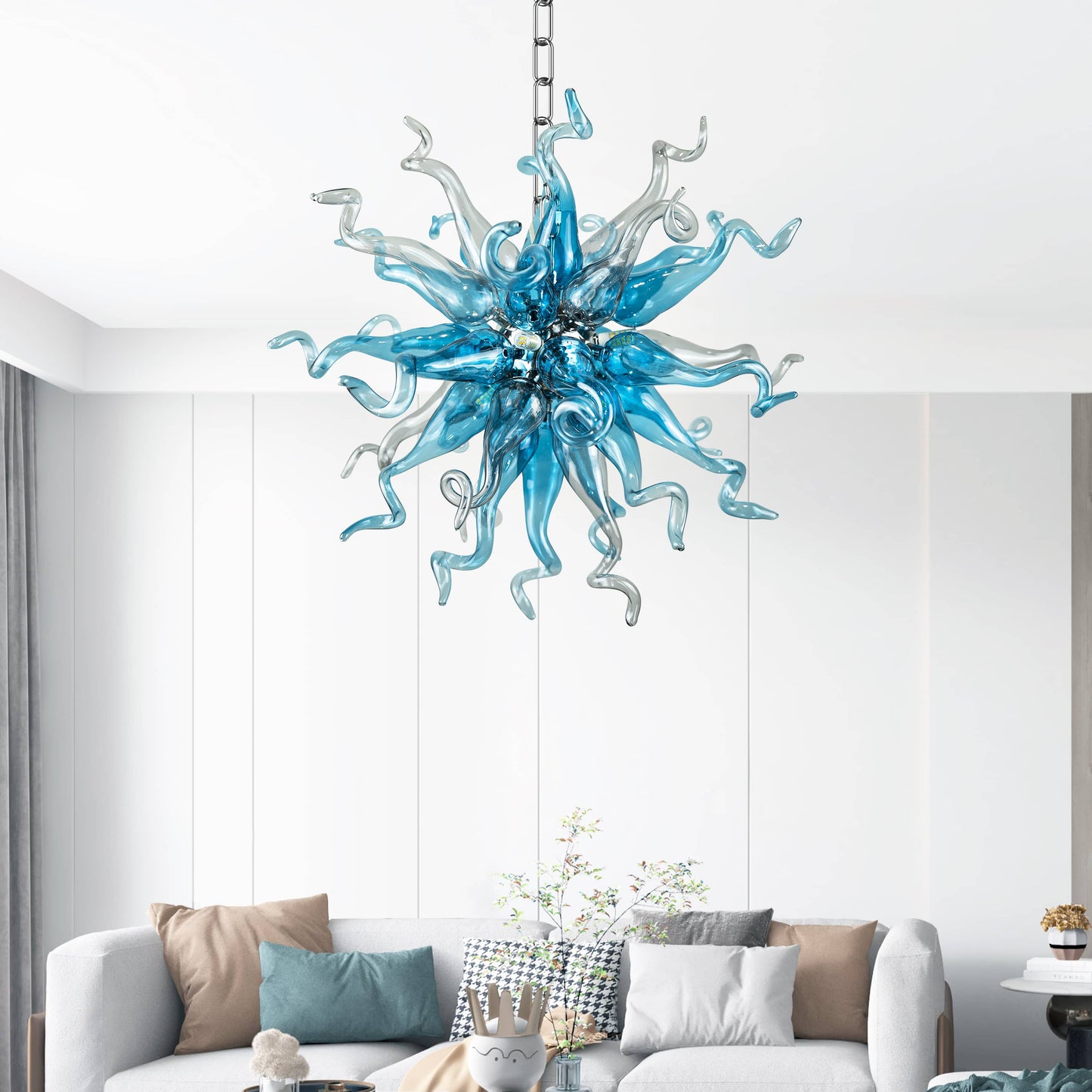 Blue Chiuhly glass chandelier hanging in a living room with a white sofa and decorative pillows.