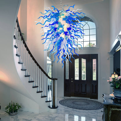Blue and white blown glass chandelier hanging in a home interior with staircase and door.