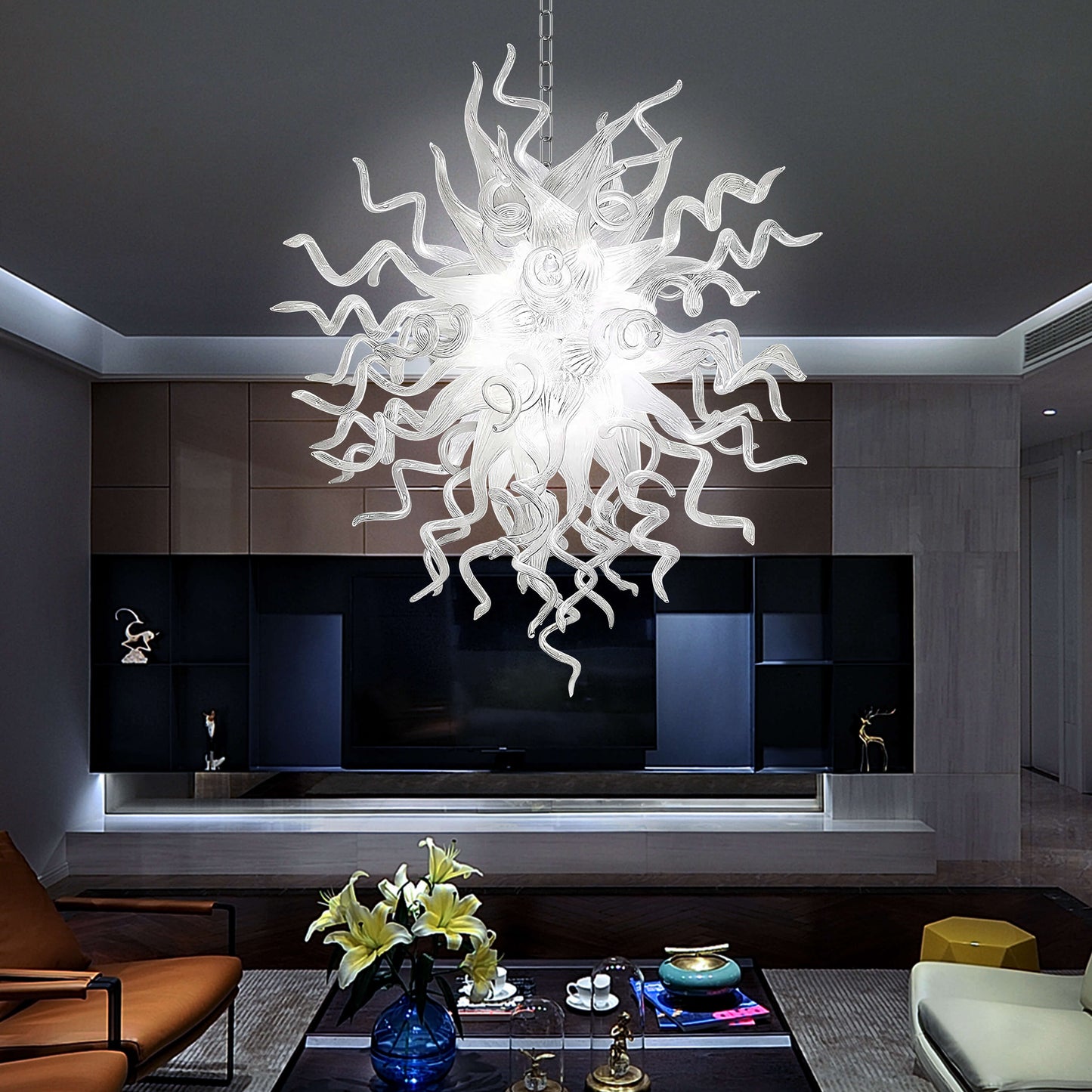 Modern white blown glass chandelier hanging in a living room with a dark wall and furniture.