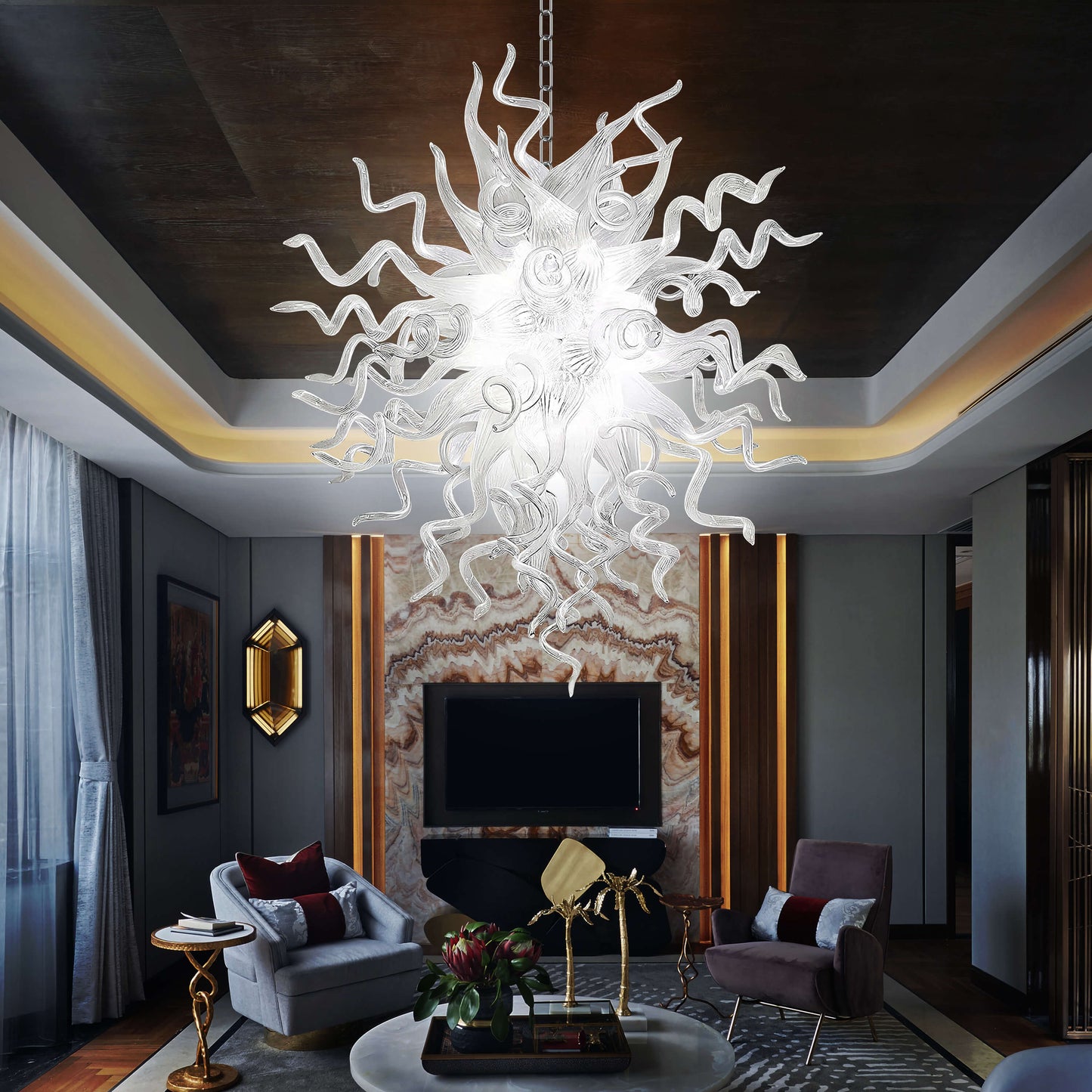 Luxurious living room with a contemporary blown glass chandelier, gray sofa, and decorative elements.