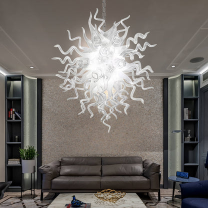 Chihuly style blown glass chandelier hanging in a living room with a brown sofa and bookshelves.