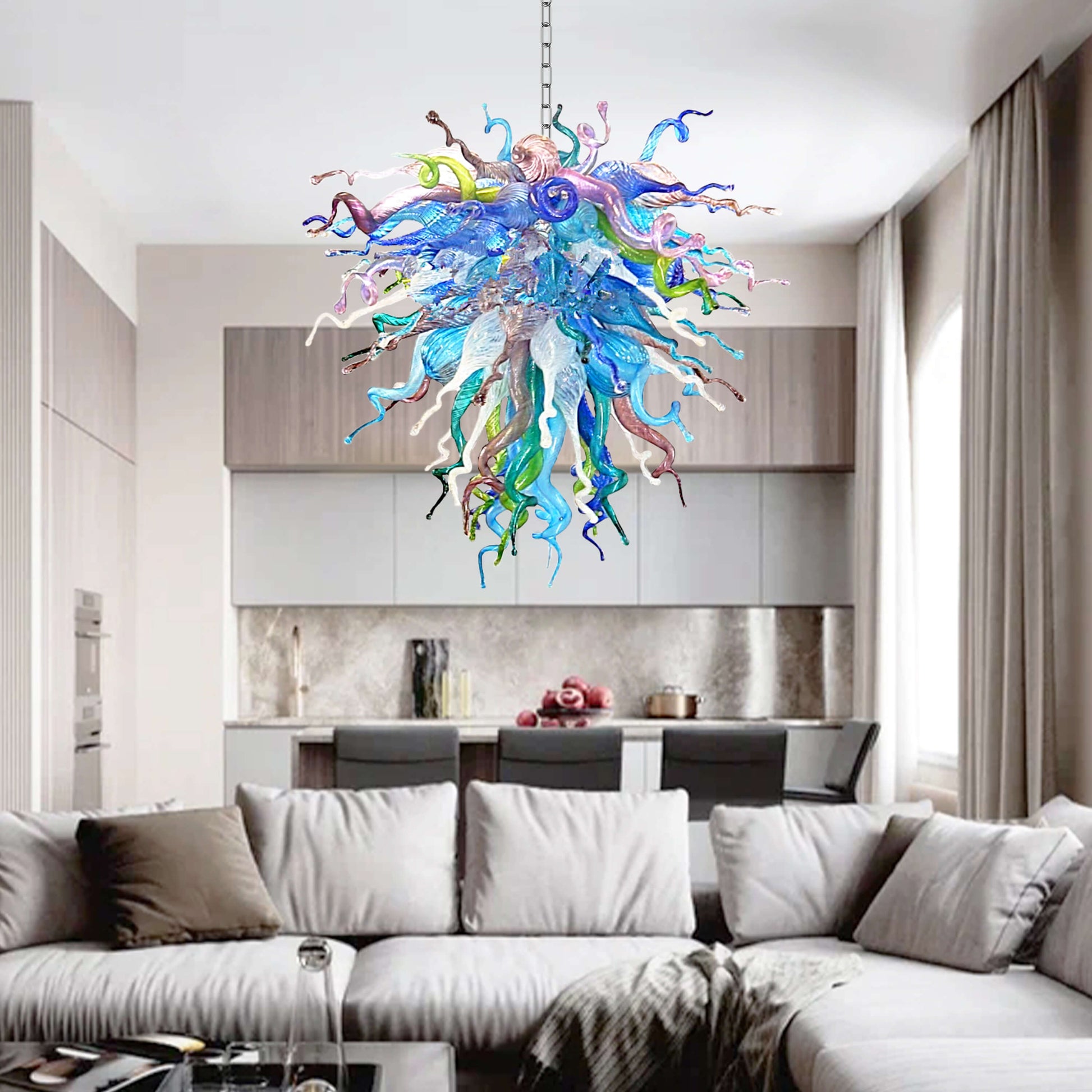 Colorful Chihuly type blown glass chandelier hanging in a modern living room with a sofa and kitchen in the background.