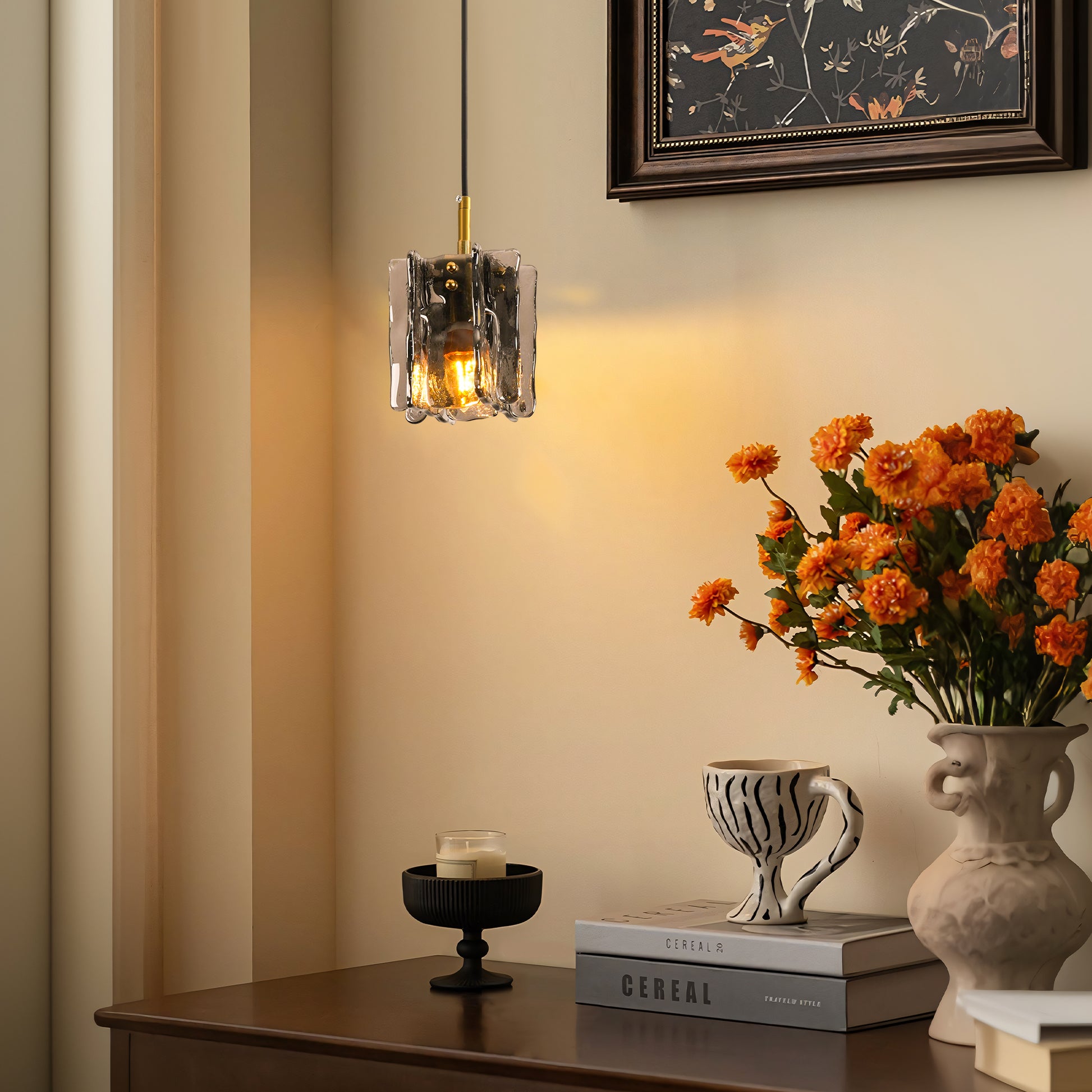 Modern 1-light mini pendant with smoke gray textured glass above a tabletop vignette with flowers and books
